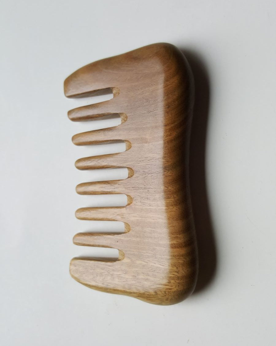 a minimalist style detangling sandalwood comb with 8 extra wide teeth. This wooden comb has a natural brown color and smooth rounded design.