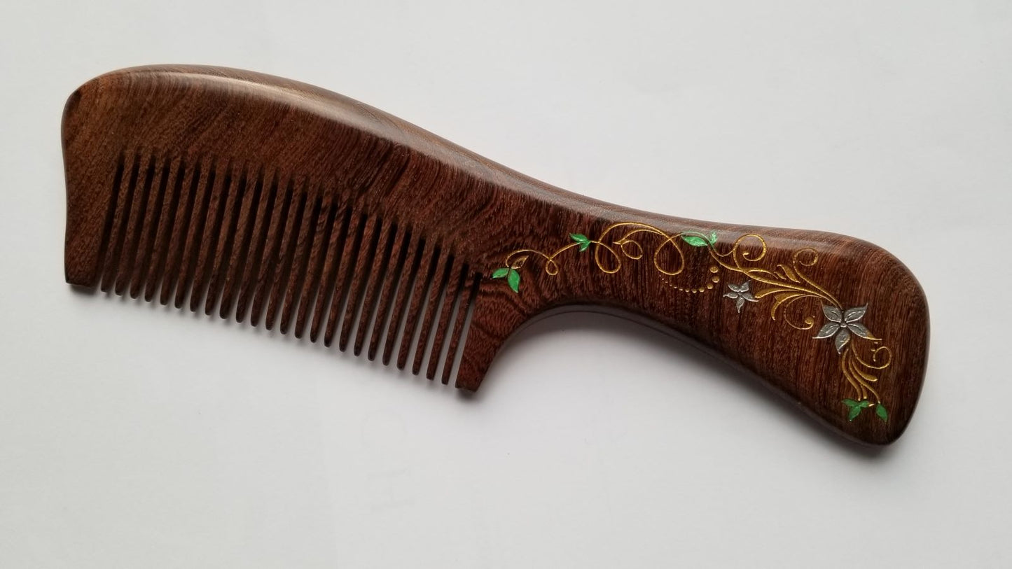 A dark brown Sucupira wood comb with an intricate floral design on the handle. This comb is designed for all hair. Great mother's day gift with gift bag
