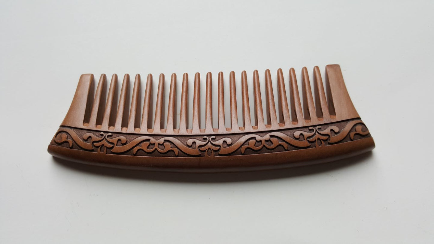 Handmade brown peach wood comb with a carved karakusa design. The comb is good for daily natural hair grooming