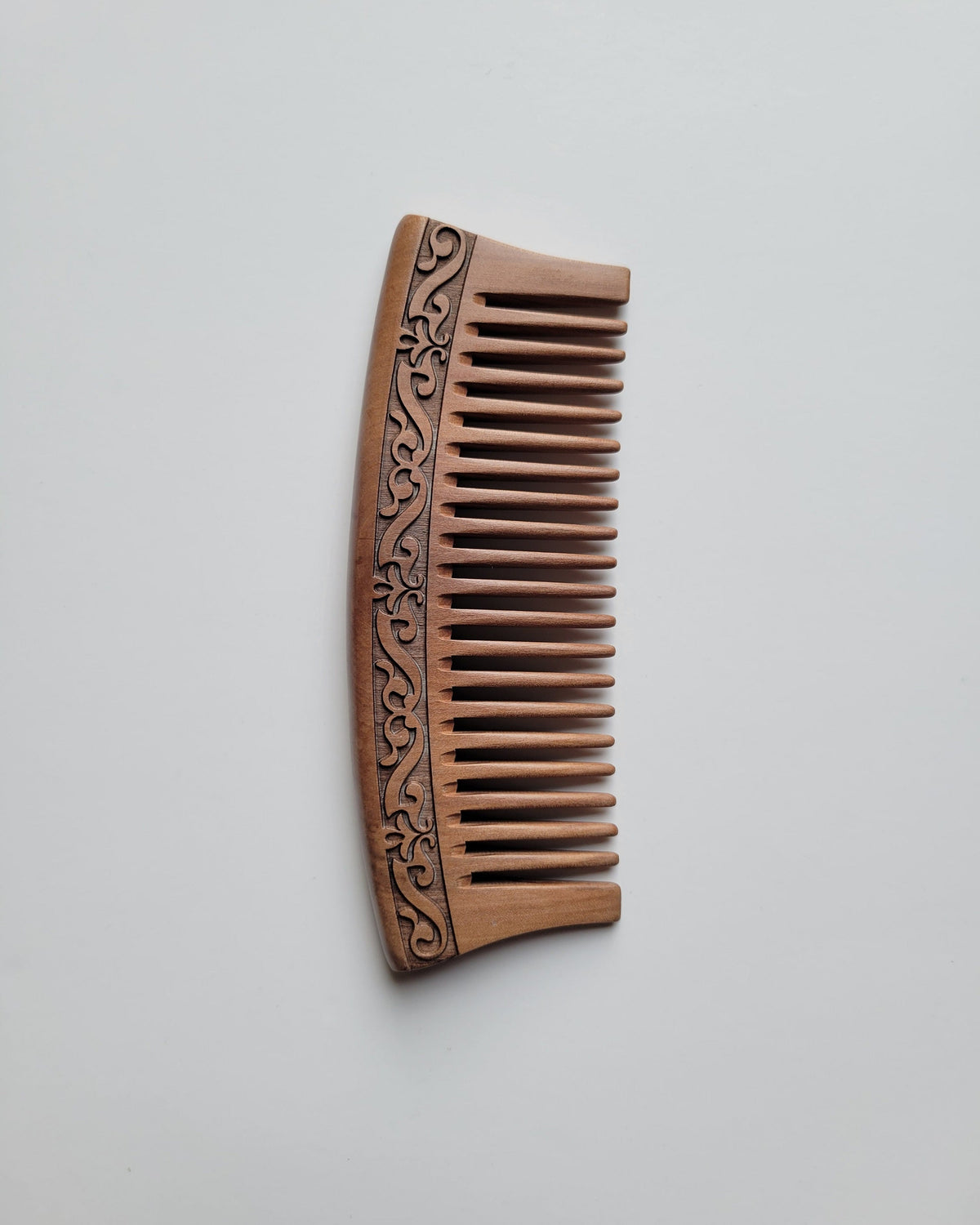 Handmade brown peach wood comb with a carved karakusa design. The comb is good for daily natural hair grooming