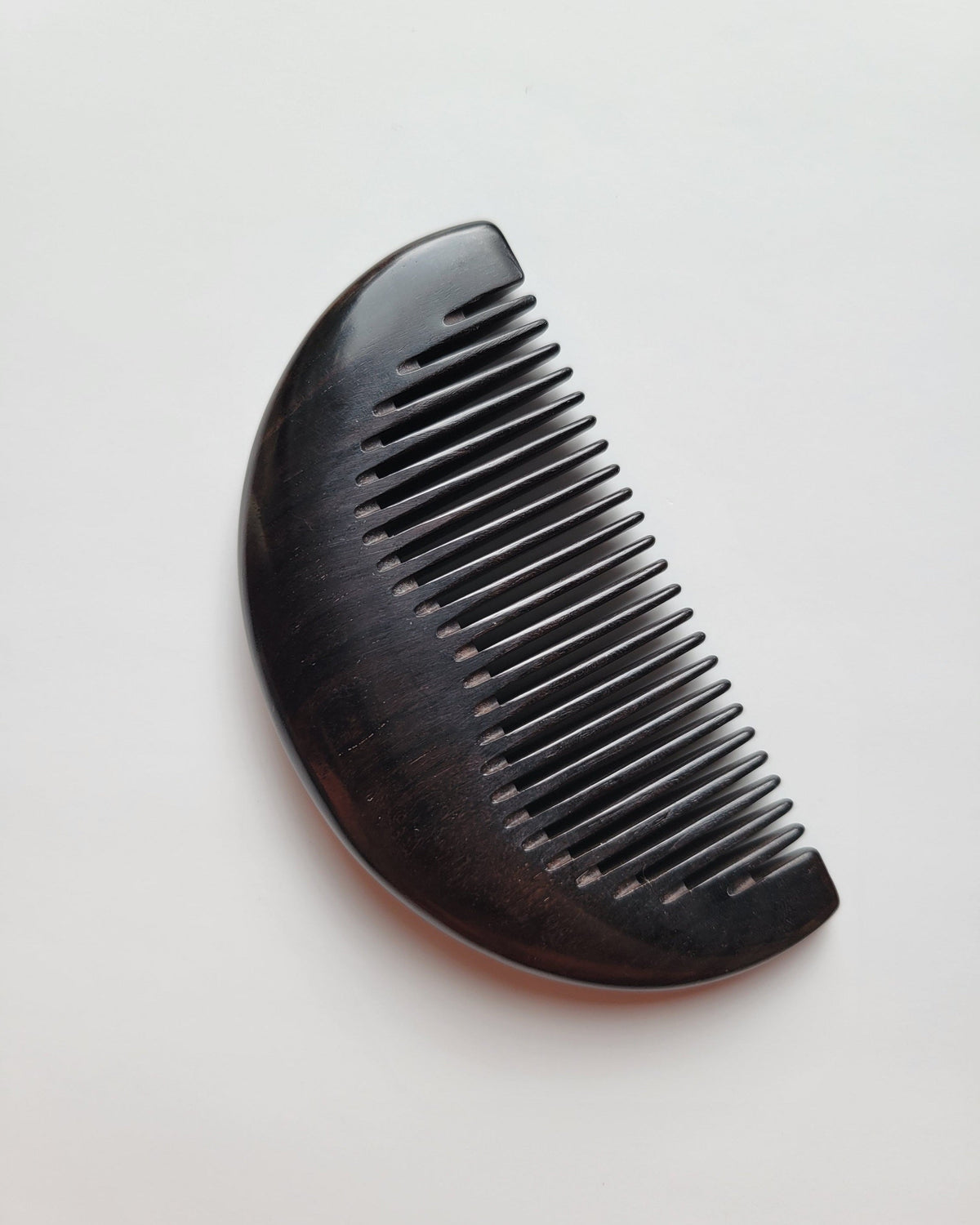 Single-piece African Ebony pocket comb, flat lay side angle showing depth and fine grain — Arakicrafts