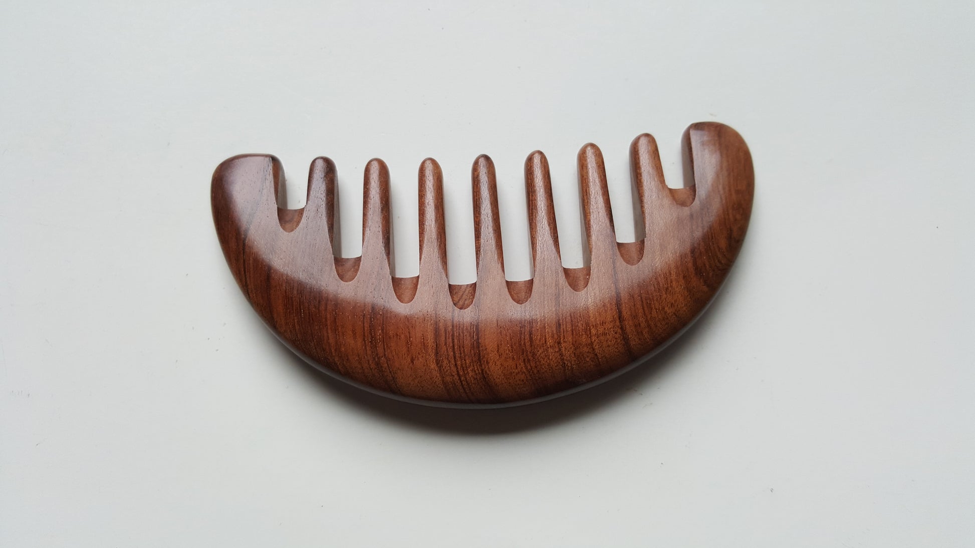 African Mopane wide tooth comb flat lay, warm reddish-brown grain with black stripe detail, anti-static natural hardwood | Arakicrafts