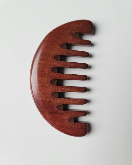 African Mopane wide tooth comb flat lay, warm reddish-brown grain with black stripe detail, anti-static natural hardwood | Arakicrafts