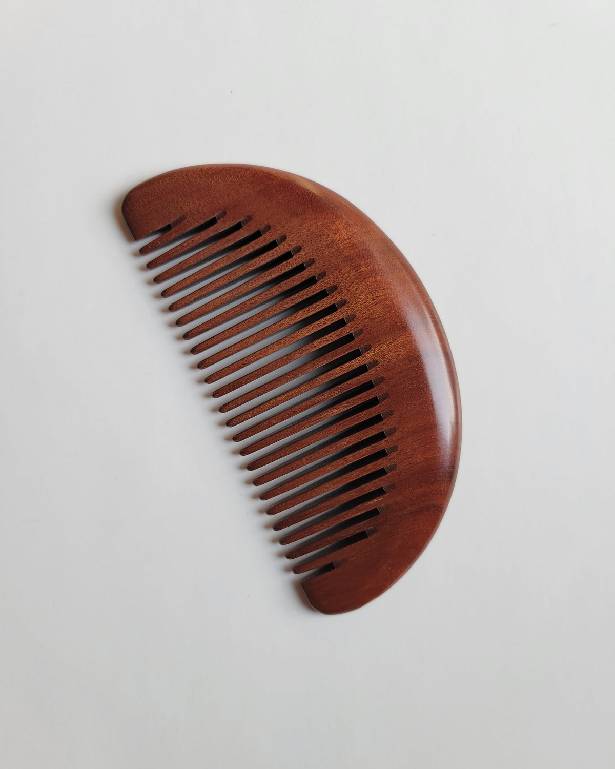 Reddish-brown wooden comb showing unique color variation and richly patterned African Mopane wood grain
