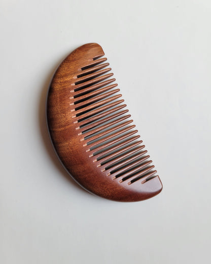 Slim half-moon pocket comb carved from a single piece of dense Mopane heartwood for travel grooming