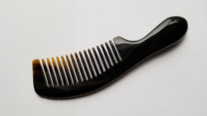 A  black horn comb with a curved handle and nicely spaced teeth. The comb's teeth transition from a light brown to black, and the handle is smooth and rounded. The comb is designed for hair care.