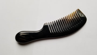 A dark brown comb with a curved handle and closely spaced teeth. The comb's teeth transition to a lighter, amber color at the tips. The handle is smooth and rounded, designed for comfortable grip. This hair care accessory is made of horn. Perfect gift for men. 