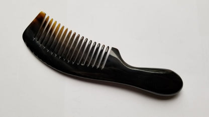A near black comb with a curved handle and closely spaced teeth. The comb transitions from black to a translucent amber color at the tips. The handle has a smooth, ergonomic design. This hair comb is designed for grooming.
