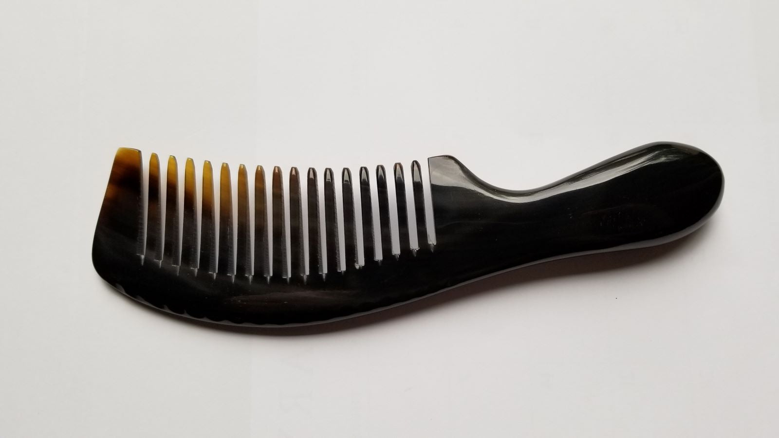 A black horn comb with a curved handle and evenly spaced teeth. The comb is designed for hair care and grooming.  Anti-static and comes with a gift back. 