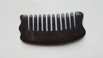 A near black buffalo comb with a curved handle and evenly spaced wide teeth. The comb is designed for hair care and grooming. The horn grain is visible, adding to the natural aesthetic. The comb is approximately 4.3 inches long. It is a one of kind unique gift for your love ones. Comes with a fabric gift bag and put it in purse or pocket. 