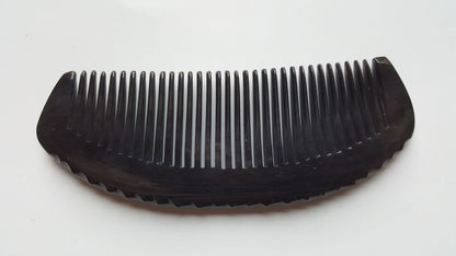 Classic buffalo horn fine-tooth comb — flat lay angled view showing organic dent handle and evenly spaced teeth