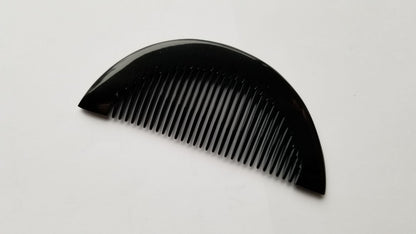 Half-moon buffalo horn comb angled left, smooth curved spine and fine tooth array