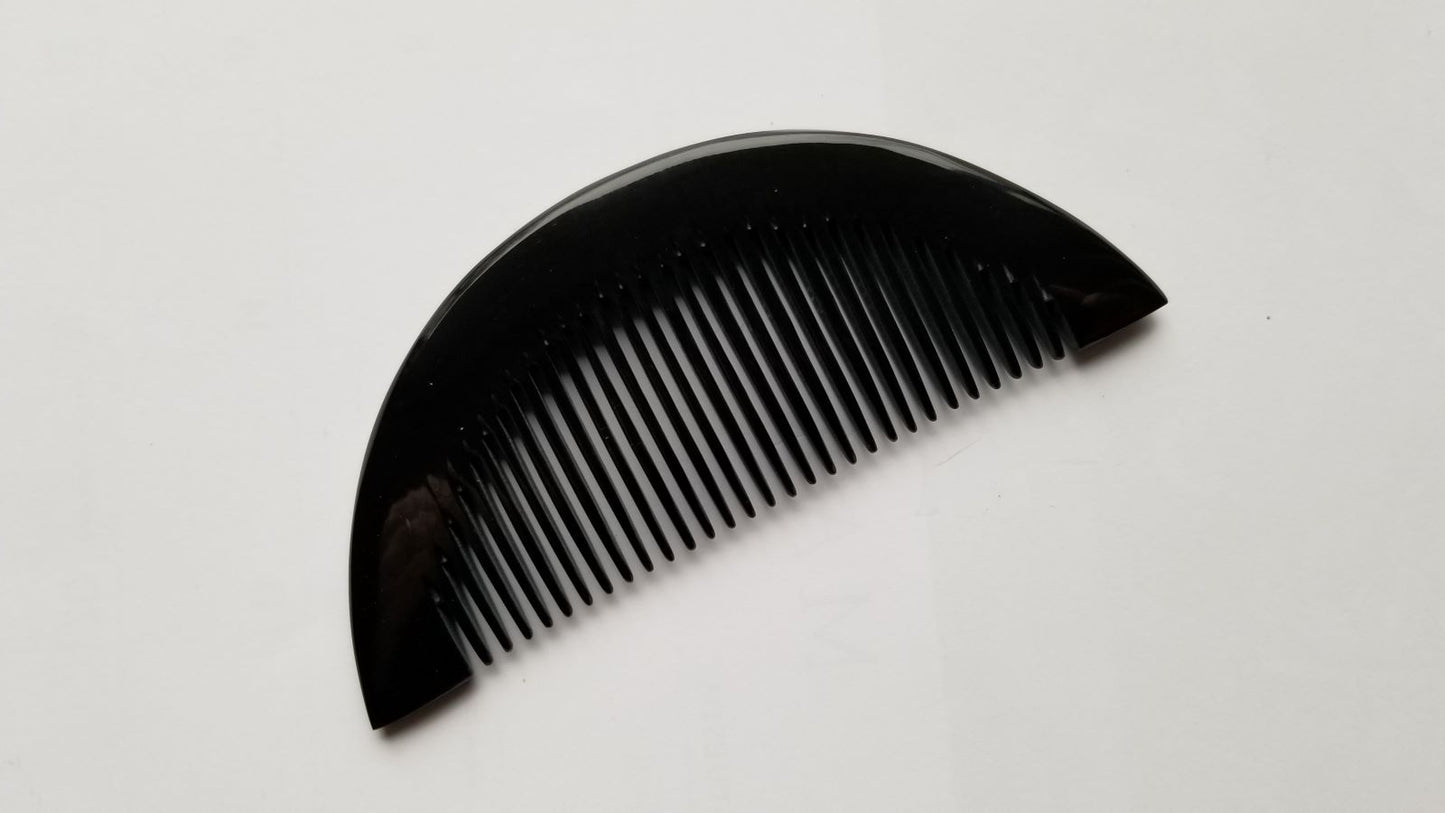 Half-moon buffalo horn comb angled right, showing symmetrical half-moon shape and horn texture