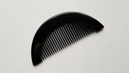 Half-moon buffalo horn comb angled right, showing symmetrical half-moon shape and horn texture