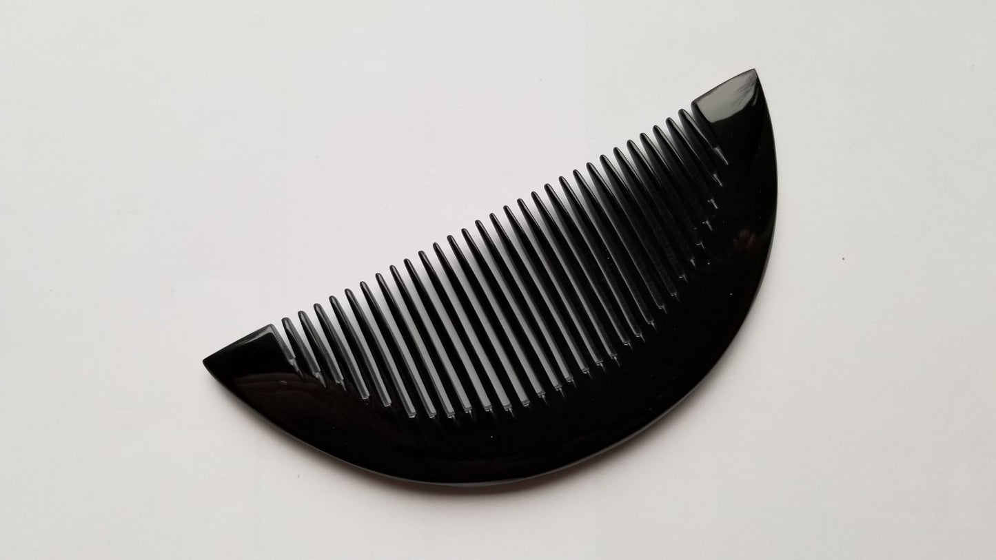 Half-moon buffalo horn comb tilted at 45 degrees, highlighting natural grain variation