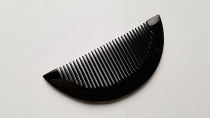 Half-moon buffalo horn comb tilted at 45 degrees, highlighting natural grain variation