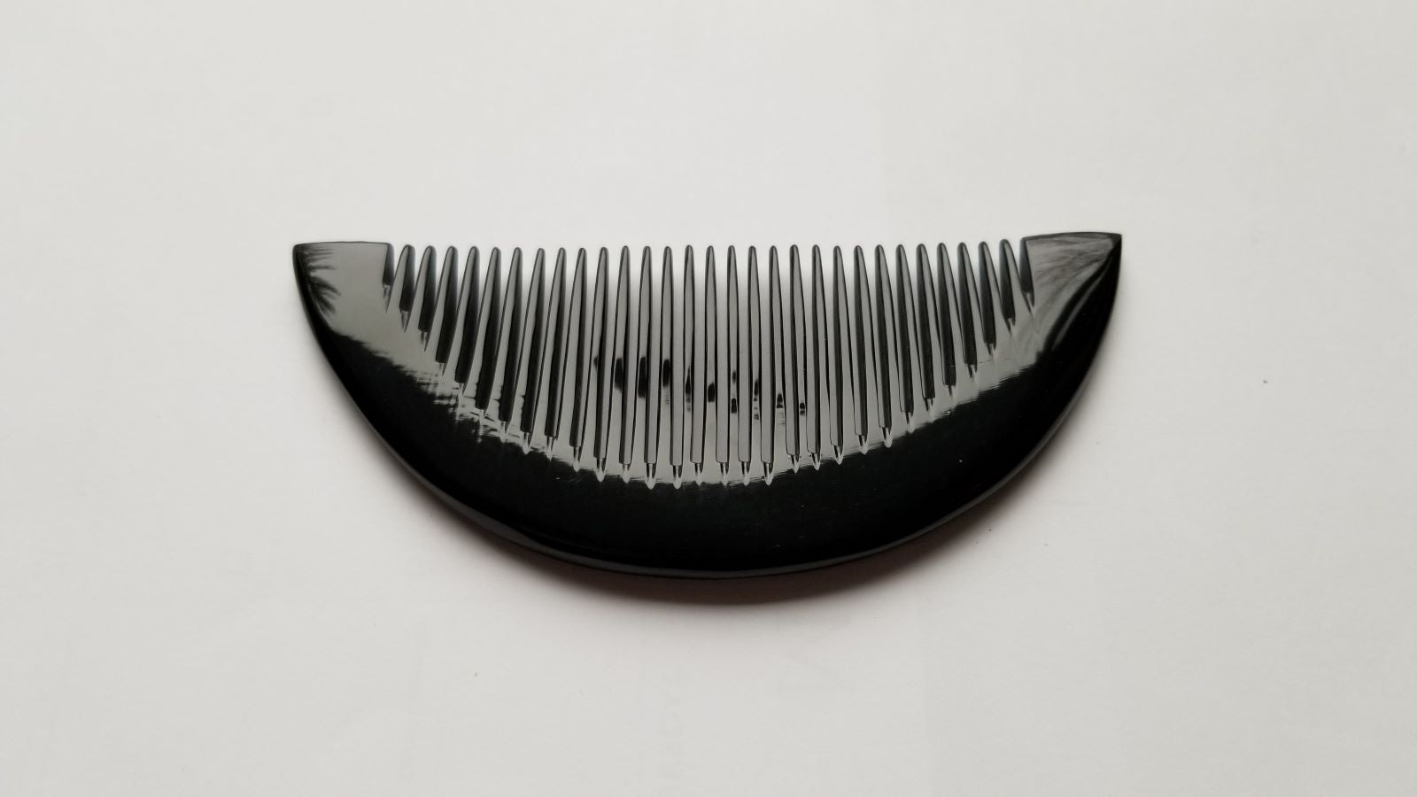 Close-up of half-moon buffalo horn comb curved spine, smooth handcrafted finish