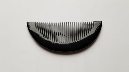 Close-up of half-moon buffalo horn comb curved spine, smooth handcrafted finish