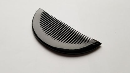 Half-moon buffalo horn comb flat lay, top view showing full symmetrical silhouette