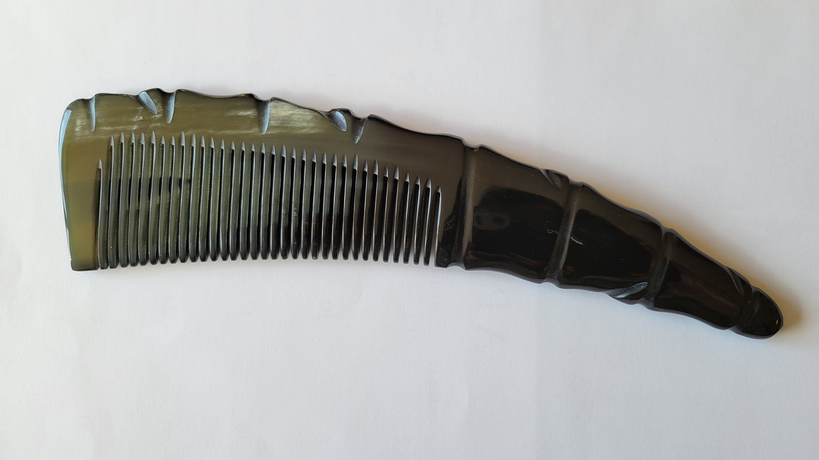 A black horn comb with a glossy finish. The comb has a unique handle design with a spiral pattern and a rounded tip. The teeth are evenly spaced and run the length of the comb.