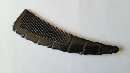 A natural horn comb with a curved handle. The comb's teeth are closely spaced, and the handle has a textured, ridged design. The color is a deep, glossy black. anti static and distribute natural oil with each use. 
