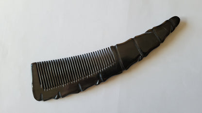 A genuine horn comb with a unique, sculpted design. The comb features closely spaced teeth and a handle with a textured, ridged pattern. The overall shape is naturally curved.  rounded teeth is good for scalp massage and stress relief.  unique gift for men