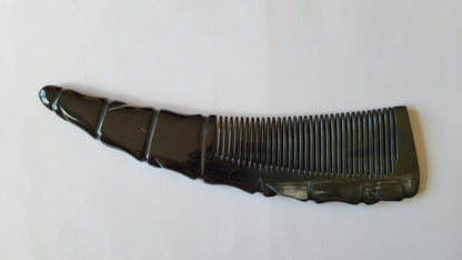 A dark color horn comb with a unique, curved handle. The handle has a textured, ridged design, and the comb teeth are closely spaced. Vintage style and good for natural hair care. 