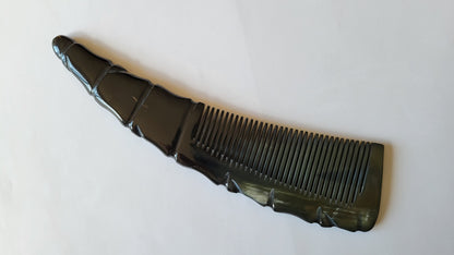 A black comb with a unique, curved design. The comb's handle has a textured, ridged pattern, and the teeth are evenly spaced.  It can reduce frizz and make your beard shine. 