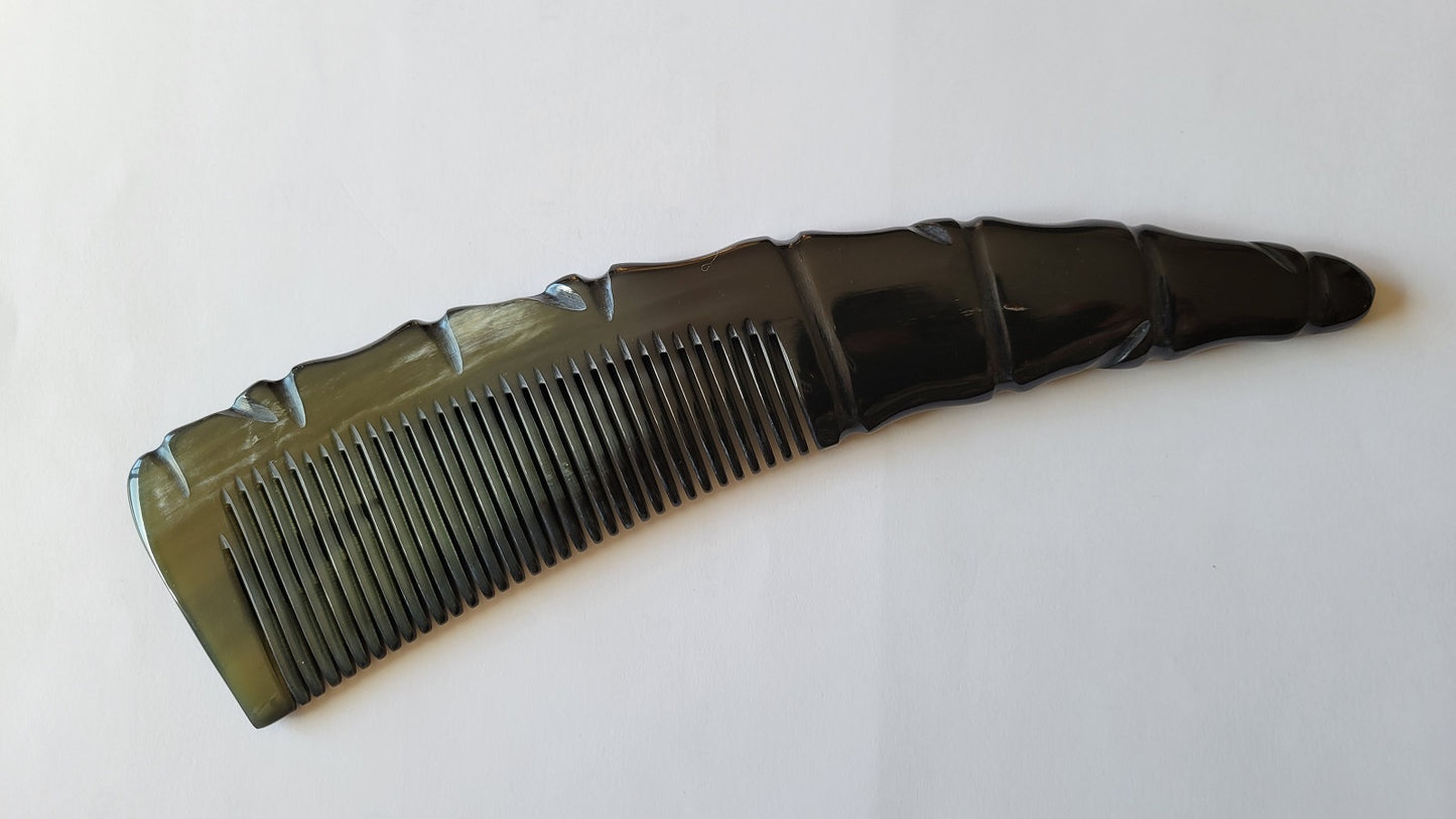 A black comb with a unique, carved handle. The comb's teeth are evenly spaced, and the handle has a textured, angular design.  A quiet eco luxury gift, biodegradable. 