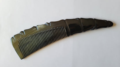 A black comb with a unique, carved handle. The comb's teeth are evenly spaced, and the handle has a textured, angular design.  A quiet eco luxury gift, biodegradable. 