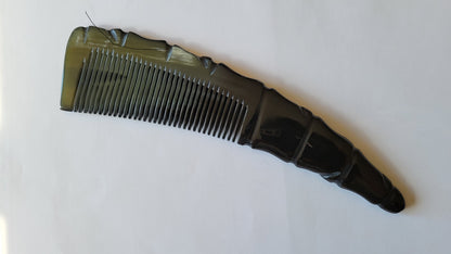 A natural horn comb with a unique, textured handle. The comb's teeth are closely spaced, and the handle has a carved, ridged design. With proper care, this comb can last for a long time and is a sustainable beauty for birthday gift for him