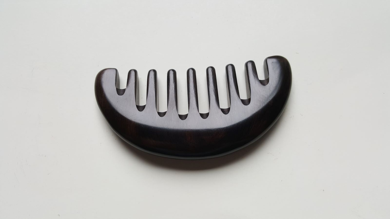 Jet-black African Ebony wide tooth comb flat lay, natural hardwood grain, anti-static hair tool | Arakicrafts