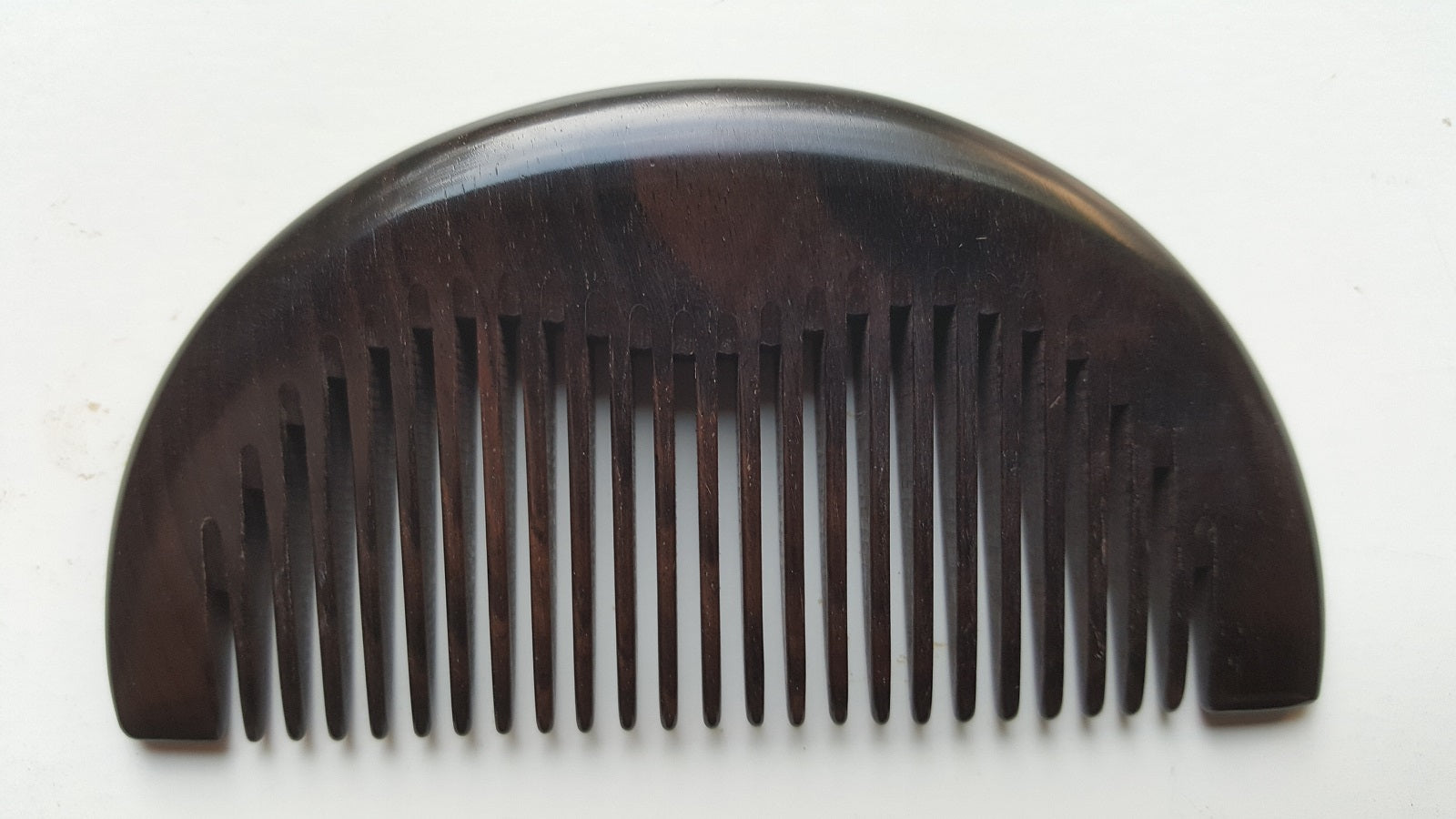 Araki half-moon wood comb in African Ebony, flat lay overhead view showing symmetrical silhouette — Arakicrafts