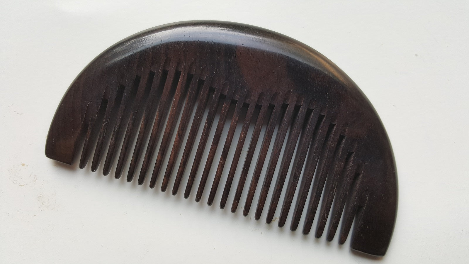 African Ebony half-moon comb, flat lay angled view highlighting fine teeth and curved edge — Arakicrafts