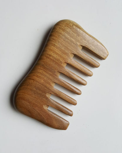 A sandalwood comb with a natural brown finish and a curved shape. This comb is for detangling and massaging.