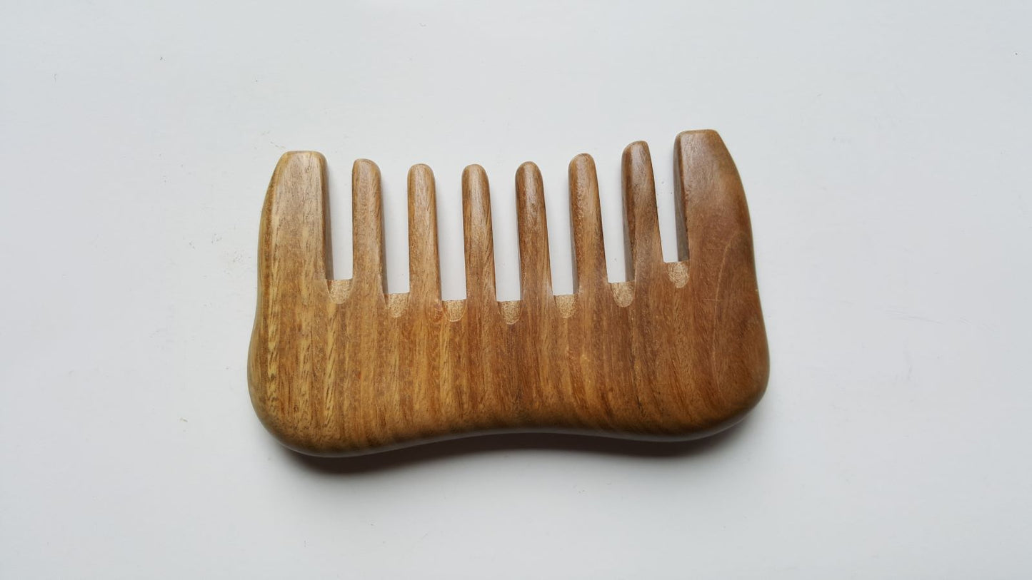 A wooden comb with a natural brown color and a smooth, curved design. The comb has eight teeth and is made of a light-colored sandalwood.