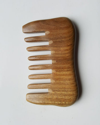 A wooden comb with a natural brown color and a smooth, curved design. The comb has eight teeth and is made of a light-colored sandalwood.