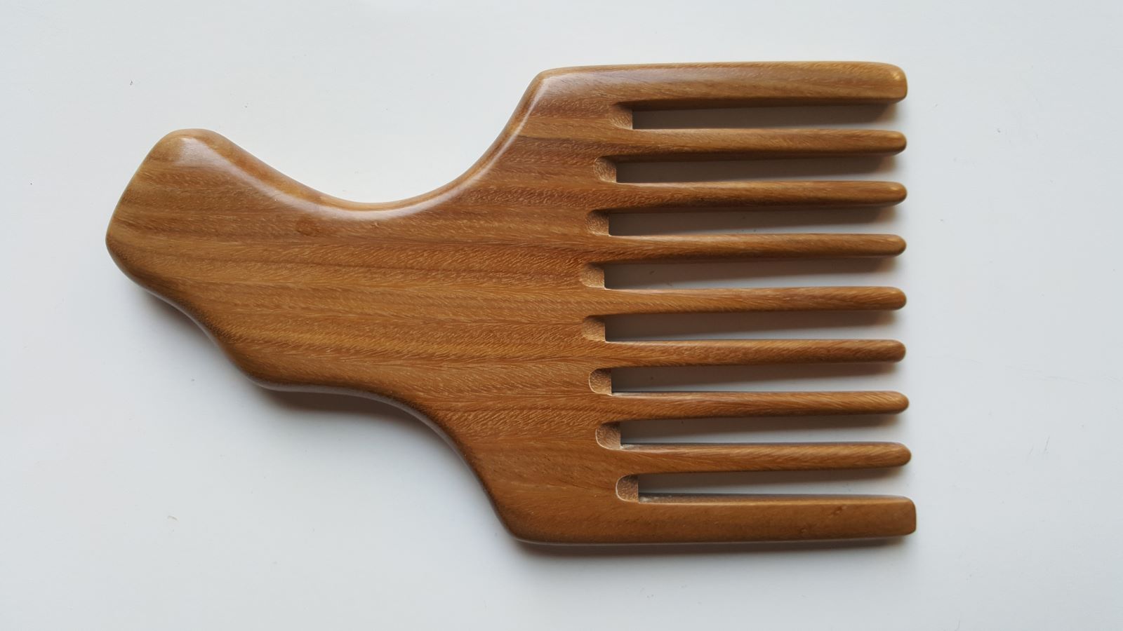 A wooden pick comb with a curved handle and nine teeth. The comb is made of light brown sandalwood with a natural grain pattern.