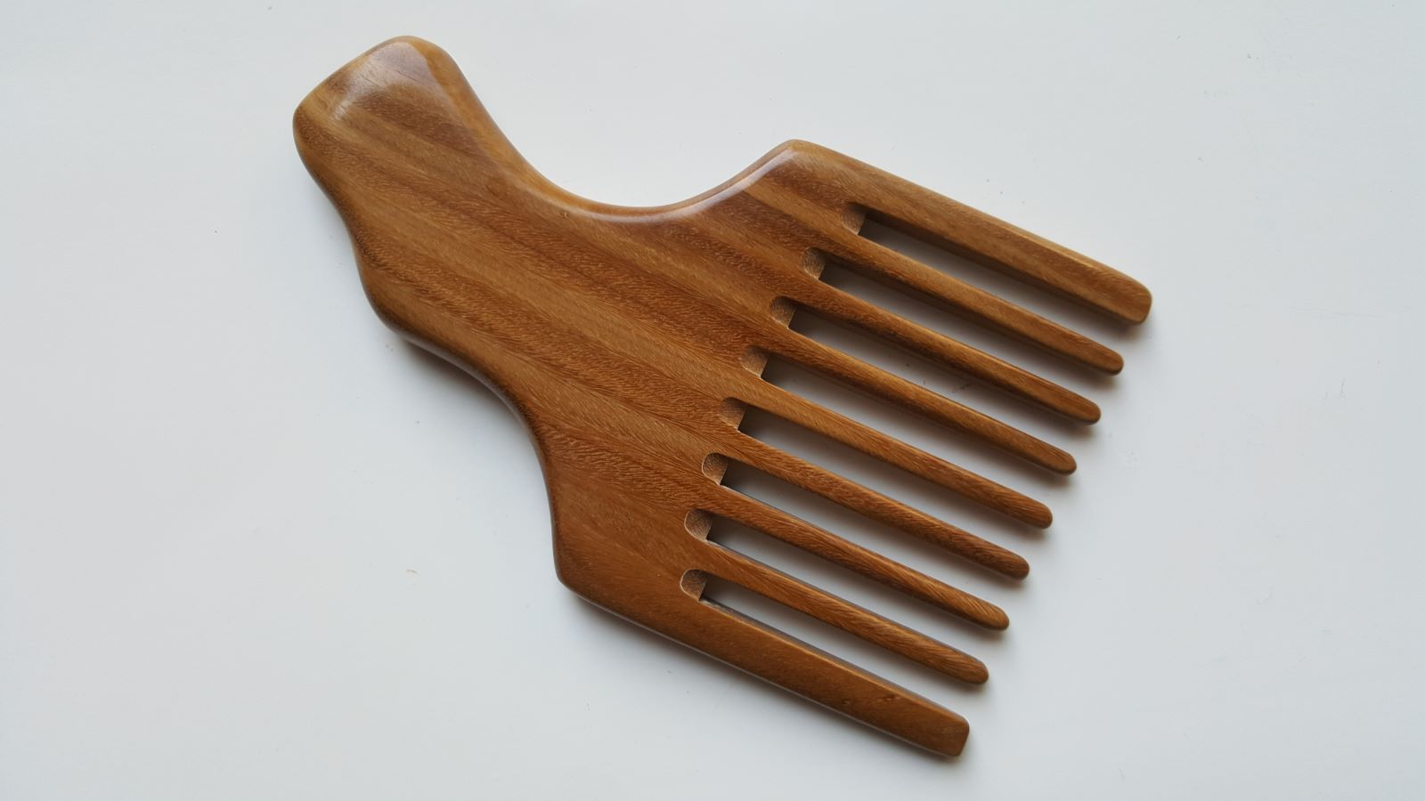 A sandalwood pick comb with a nice curved handle and a row of nine long teeth. This comb has  a natural grain pattern and is one of a kind piece.  Great gift for long hair lovers!