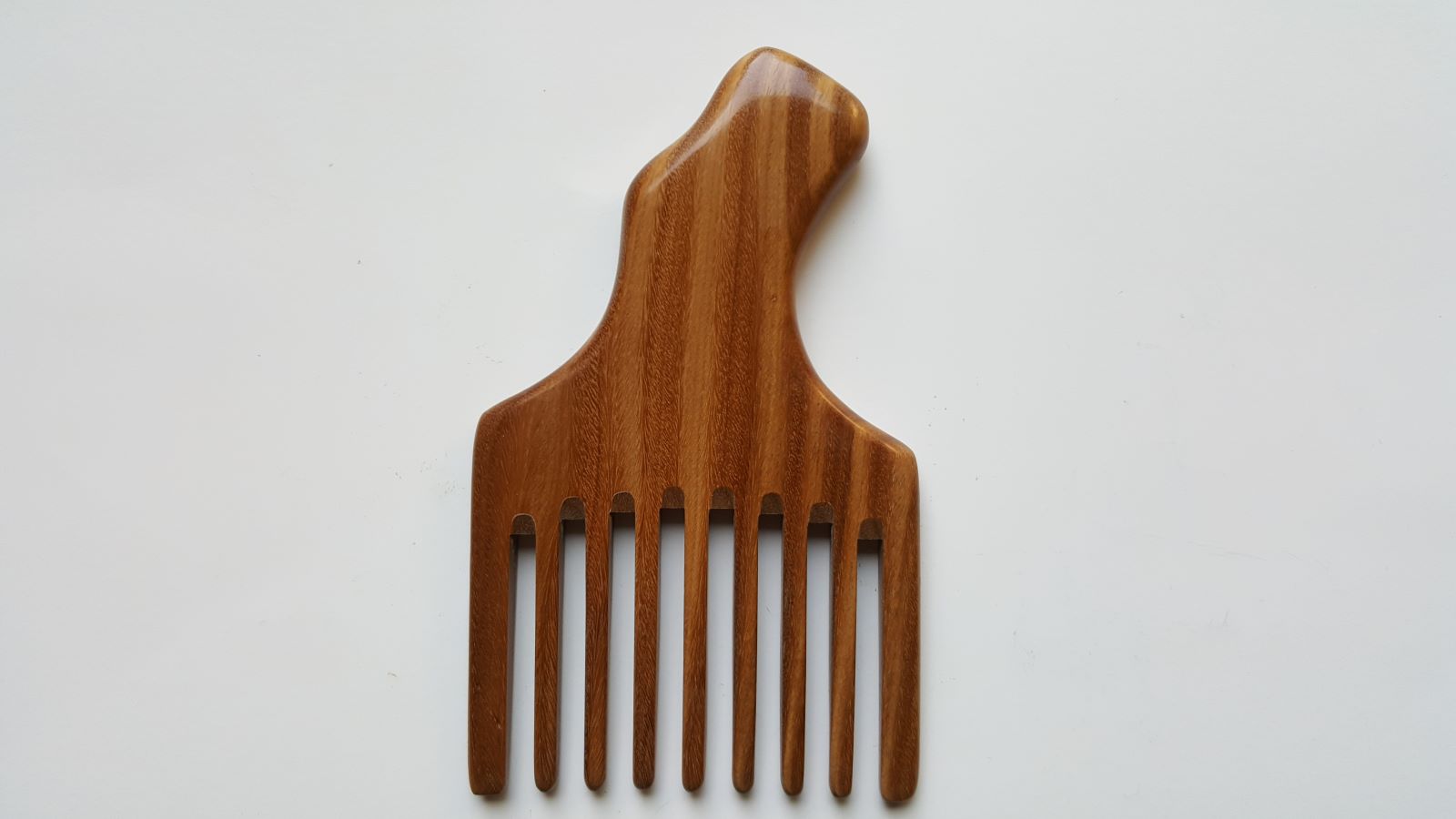 A sandalwood pick comb with a curved handle and nine teeth. The comb  has a smooth finish and comes with a fabric gift bag.  Gift for her!