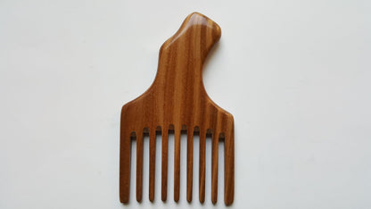 A sandalwood pick comb with a curved handle and nine teeth. The comb  has a smooth finish and comes with a fabric gift bag.  Gift for her!
