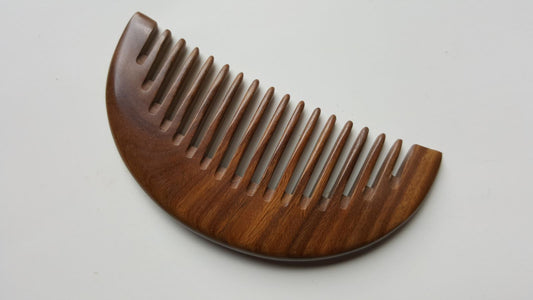 A brown wooden comb with a half-moon shape and rounded teeth. It has beautiful wood grain pattern and smooth finish.