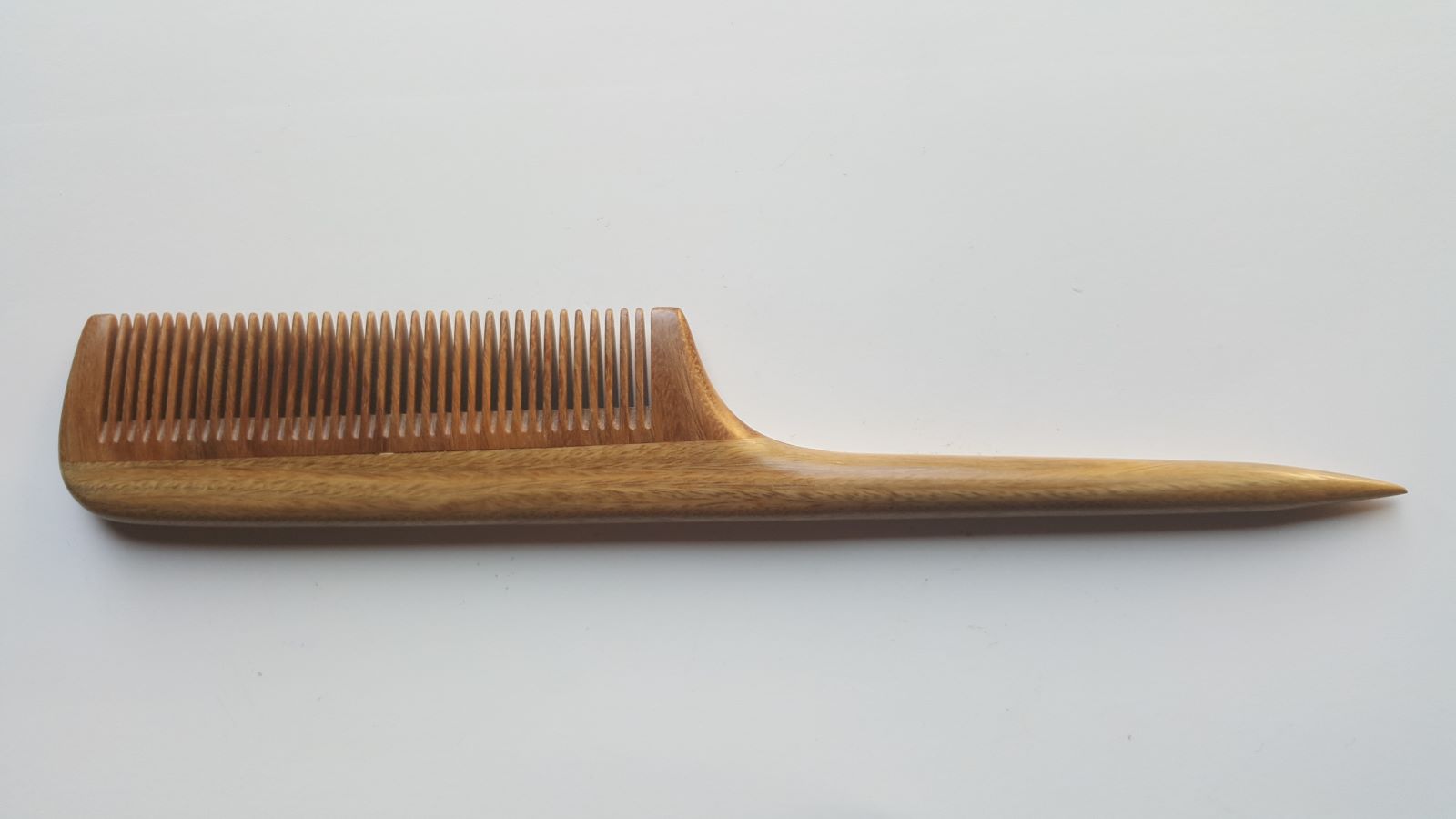 A greenish brown wooden comb with a long, thin handle. The comb has a rounded edge and a pointed tip.