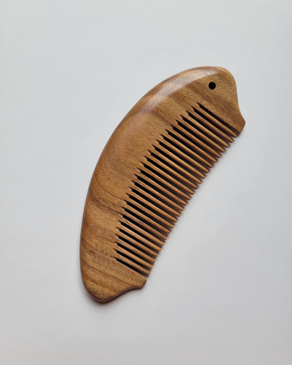 Green sandalwood fish comb angled view showing tooth depth and fish body thickness, fine 0.15 cm spacing for all hair types