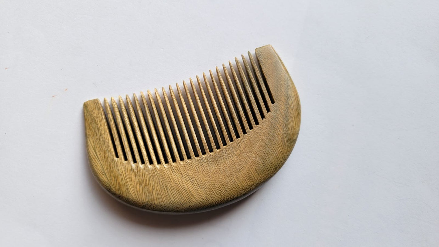 A wooden comb with a curved handle and fine teeth. The comb is made of light brown wood and has a smooth, polished finish. The teeth are evenly spaced and designed for daily hair care on the goo The comb is a hair care accessory.