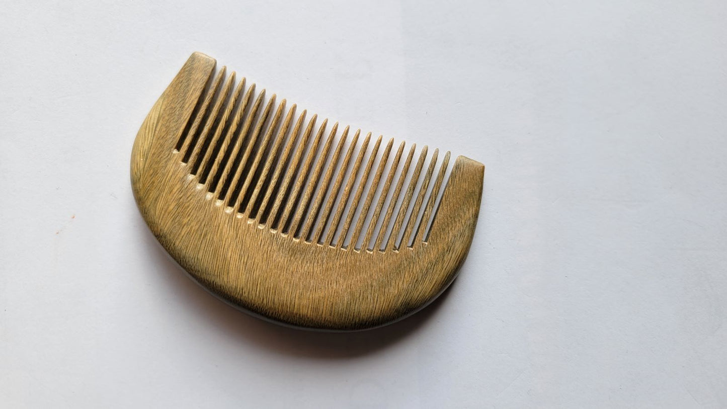 A wooden comb with a curved handle and fine teeth. The comb is made of a light-colored wood with a visible grain pattern. The teeth are evenly spaced and extend from the curved handle. Perfect gift for her!