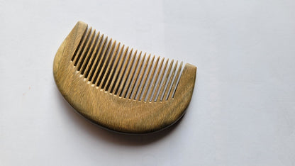 A wooden comb with a curved handle and fine teeth. The comb is made of a light-colored wood with a visible grain pattern. The teeth are evenly spaced and extend from the curved handle. Perfect gift for her!