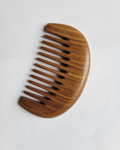 A travel size brown wooden comb with a curved handle section and rounded teeth. this comb has beautiful brown wood grain and suitable for on-the-go hair and beard grooming. Gift for him!