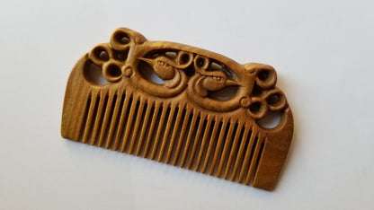 East Asian Phoenix Sandalwood Comb flat lay — side angle highlighting carved phoenix detail and fine tooth spacing on green sandalwood body