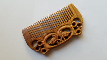 East Asian Phoenix Sandalwood Comb flat lay — diagonal angle showing fine teeth and carved phoenix detail on sandalwood. It was designed for people who appreciate natural hair care. 